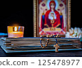 The time for prayer. Wooden Rosary on an ancient prayer book. Icon of the Mother of God and Jesus. Lighted candle 125478977