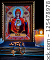 The time for prayer. Wooden Rosary on an ancient prayer book. Icon of the Mother of God and Jesus. Lighted candle 125478978