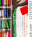Set of multi-colored cotton threads and fragment of colorful cross-stitch embroidere. Colorful mouline threads. Top view 125478983
