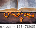 Wooden rosary and open Bible in the background 125478985