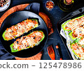 Stuffed zucchini with vegetables and cheese on a plate, top view 125478986