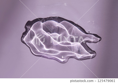 A drop of oil serum on a purple background with beautiful highlights. A drop of oil serum on a purple background with beautiful highlights. 125479061