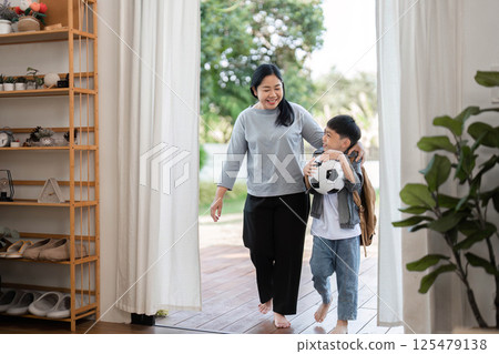Outdoor Adventure and School Preparation. A mother and son stepping out together after packing for school. 125479138