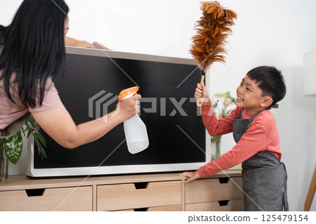 Family Cleaning and Home Care. A mother and son joyfully cleaning a TV stand together. Family Cleaning and Home Care. A mother and son joyfully cleaning a TV stand together. 125479154
