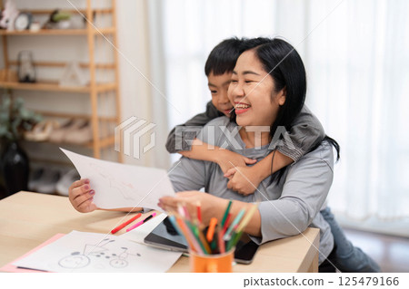 Back to School and Creativity. A mother and son share a loving moment as they review his artwork together. 125479166
