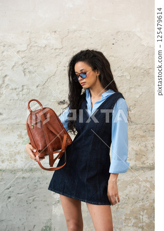 A Chic Outfit Featuring a Bright Brown Backpack Paired with Stylish and Trendy Dress and Blue Shirt A Chic Outfit Featuring a Bright Brown Backpack Paired with Stylish and Trendy Dress and Blue Shirt 125479614