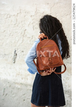 A Chic Outfit Featuring a Bright Brown Backpack Paired with Stylish and Trendy Dress and Blue Shirt A Chic Outfit Featuring a Bright Brown Backpack Paired with Stylish and Trendy Dress and Blue Shirt 125479624