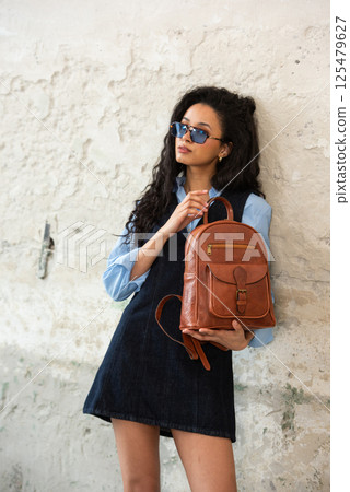A Chic Outfit Featuring a Bright Brown Backpack Paired with Stylish and Trendy Dress and Blue Shirt A Chic Outfit Featuring a Bright Brown Backpack Paired with Stylish and Trendy Dress and Blue Shirt 125479627
