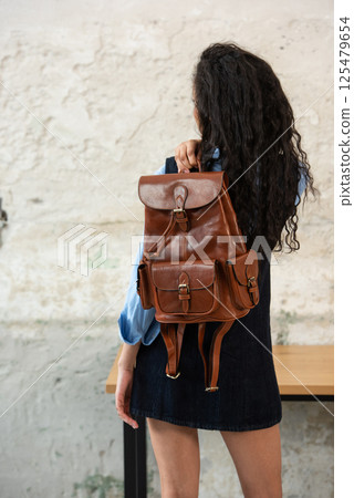 A Chic Outfit Featuring a Bright Brown Backpack Paired with Stylish and Trendy Dress and Blue Shirt A Chic Outfit Featuring a Bright Brown Backpack Paired with Stylish and Trendy Dress and Blue Shirt 125479654