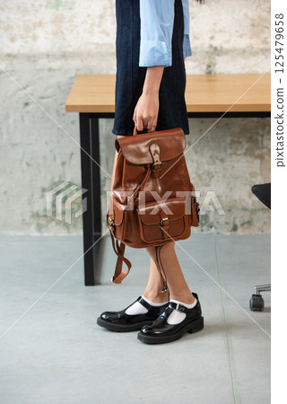 A Chic Outfit Featuring a Bright Brown Backpack Paired with Stylish and Trendy Dress and Blue Shirt A Chic Outfit Featuring a Bright Brown Backpack Paired with Stylish and Trendy Dress and Blue Shirt 125479658
