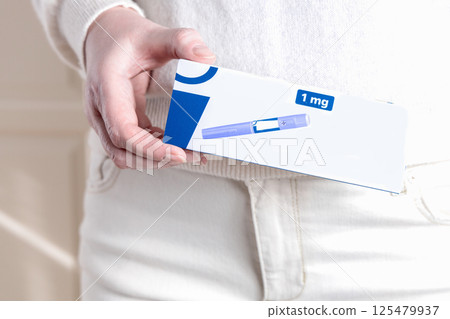 Woman in white clothes holding a pack of Ozempic Insulin injection pen for diabetics and weight loss. Woman in white clothes holding a pack of Ozempic Insulin injection pen for diabetics and weight loss. 125479937