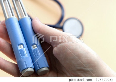 Women's hands holding Insulin injection pen for diabetics and weight loss. 125479938