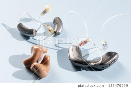 Various modern hearing aids on a blue background 125479939