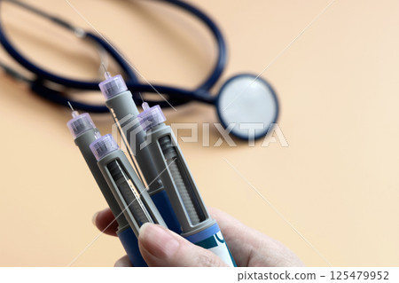 Women's hands holding Insulin injection pen for diabetics and weight loss. Women's hands holding Insulin injection pen for diabetics and weight loss. 125479952