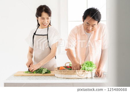 A couple in their 50s cooking in the kitchen A couple in their 50s cooking in the kitchen 125480088