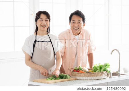 A couple in their 50s cooking in the kitchen 125480092