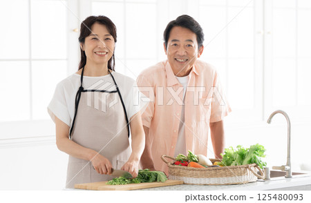 A couple in their 50s cooking in the kitchen A couple in their 50s cooking in the kitchen 125480093