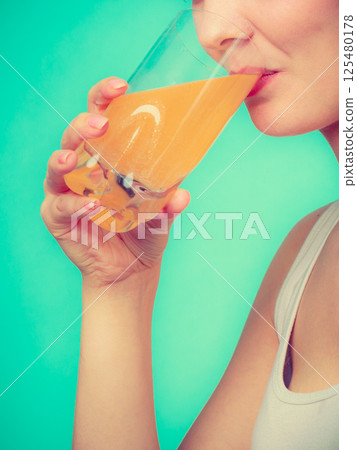 Woman drinking orange flavored drink or juice Woman drinking orange flavored drink or juice 125480178