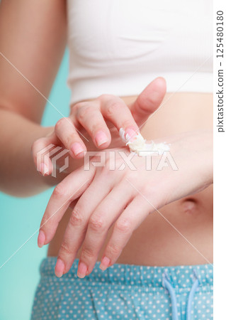 Woman putting white cream on hand 125480180