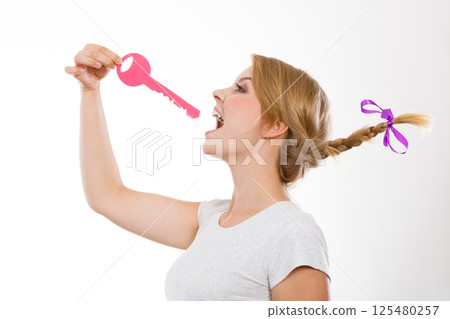 Teenage girl with braid biting key Teenage girl with braid biting key 125480257