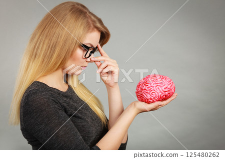 Woman thinking and holding fake brain Woman thinking and holding fake brain 125480262