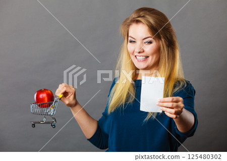 Happy woman holding shopping basket with fruits 125480302