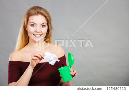 Woman putting paper into small trash can 125480313