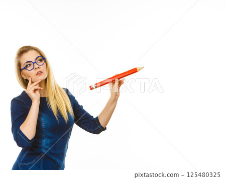 Woman confused thinking, big pencil in hand Woman confused thinking, big pencil in hand 125480325