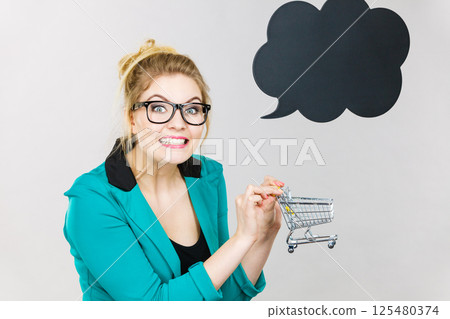 Happy business woman holding small tiny shopping cart 125480374