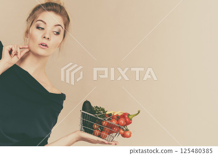 Woman with vegetables, thinking face expression 125480385