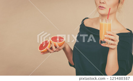 Happy woman holding fresh orange juice 125480387