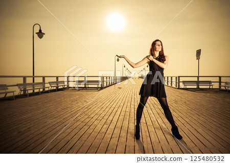 woman posing on pier at sunrise woman posing on pier at sunrise 125480532