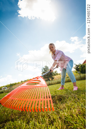 Unusual angle of woman raking leaves Unusual angle of woman raking leaves 125480722
