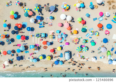 Aerial view of colorful umbrellas on beach, people in blue sea Aerial view of colorful umbrellas on beach, people in blue sea 125480896