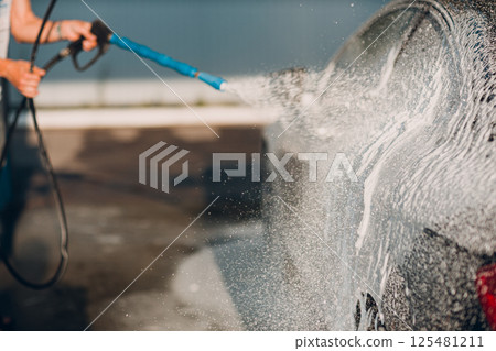 Worker washing car at self-service car wash 125481211