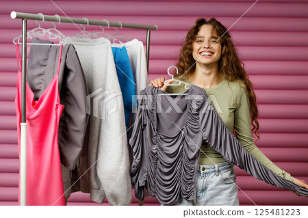 Young woman choosing clothes at fitting room. Shopping concept 125481223