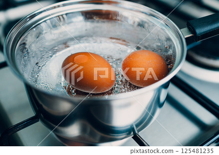 Saucepan stainless steel with boiling eggs breakfast in a water on a gas stove. Saucepan stainless steel with boiling eggs breakfast in a water on a gas stove. 125481235