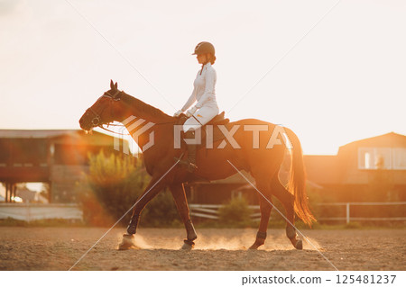 Woman rider jockey in helmet and white uniform preparing horse racing Woman rider jockey in helmet and white uniform preparing horse racing 125481237