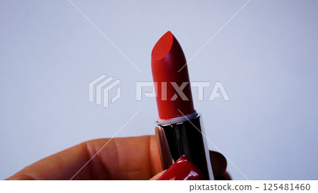A woman twirls red lipstick in her hand. A woman twirls red lipstick in her hand. 125481460