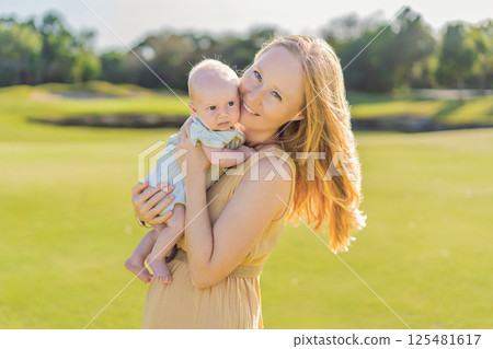 Mother and newborn baby on a meadow in the park. Tender bonding moment in nature. Parenthood, love, and family connection concept 125481617