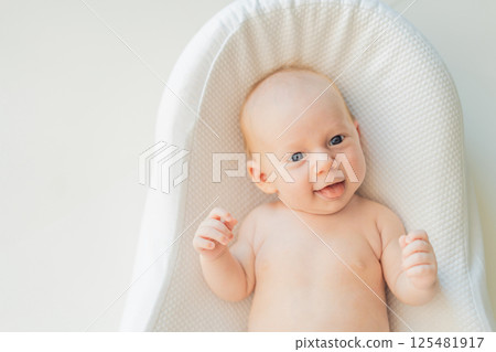 Newborn baby comfortably resting in a cozy baby nest. Safe and peaceful sleep concept for infants 125481917