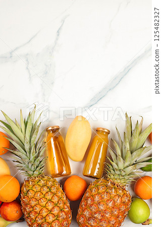 Summer tropical fruits and juices on marble table, source of vitamin C, banner for shop, healthy vegan products for healthy lifestyle, detox diet and weight loss concept, shop advertisement. 125482327