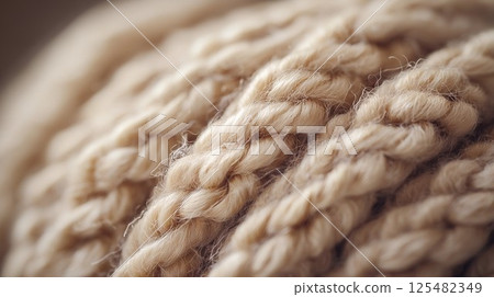 Close up of a knitted item with a fuzzy texture. The yarn is a light tan color 125482349