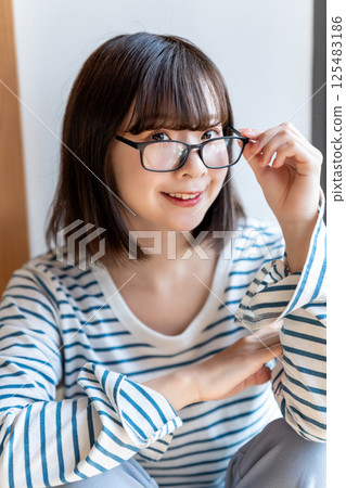 A young woman wearing glasses relaxing in a room 125483186