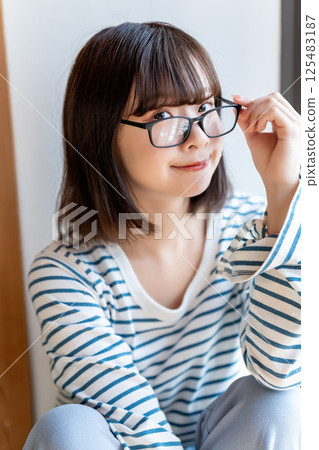 A young woman wearing glasses relaxing in a room 125483187
