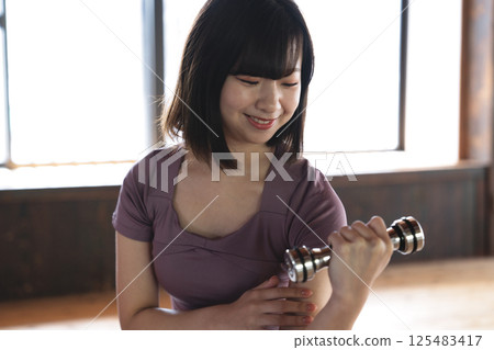 A young woman training with a dumbbell A young woman training with a dumbbell 125483417