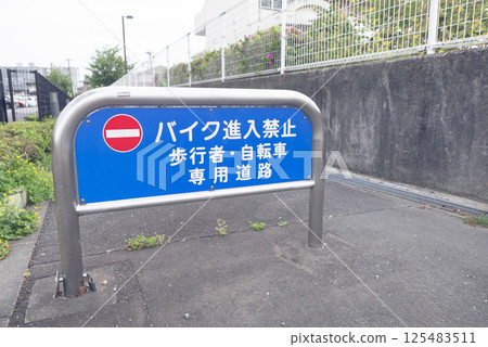 Photograph of a pedestrian and bicycle path in a residential area, and a vehicle stop sign prohibiting motorcycles from entering 125483511