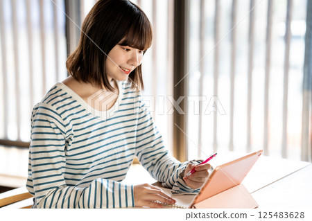 使用平板電腦學習的年輕女性 使用平板電腦學習的年輕女性 125483628