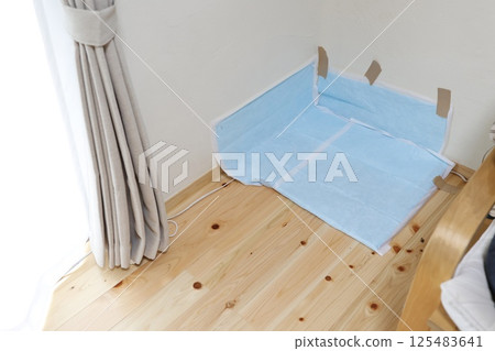 A dog sheet is laid out in the corner of the room and secured to the wall with duct tape. A dog sheet is laid out in the corner of the room and secured to the wall with duct tape. 125483641