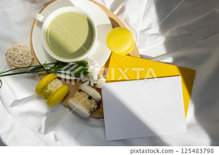Empty white envelope letter mockup template Green latte match and macaron on messy bed. Concept of holiday breakfast morning tea drink. Cozy minimalist superfood vibrant colors healthy eating. Organic Empty white envelope letter mockup template Green latte match and macaron on messy bed. Concept of holiday breakfast morning tea drink. Cozy minimalist superfood vibrant colors healthy eating. Organic 125483798
